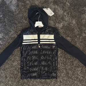 Moncler cardigan jacka med huva - Säljer nu min moncler cardigan som jag knappt har använt. Den är köpt på nk i stockholm. Den är i väldigt bra skick inga märken eller något liknande den är som ny. Kvitto finns