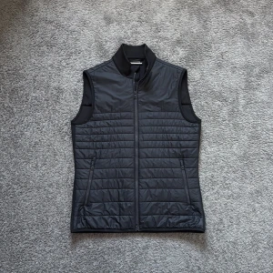 Svart quiltad dunväst J.Lindeberg  - Svart quiltad dunväst från J.Lindeberg i storlek S. Västen har hög krage, två dragkedjefickor och hel dragkedja framtill. Snyggt stilren design med horisontella sömmar och lätt glansig yta. Perfekt lager-på-lager-plagg för kyligare dagar. Tar även emot byten. Kom med pris förslag