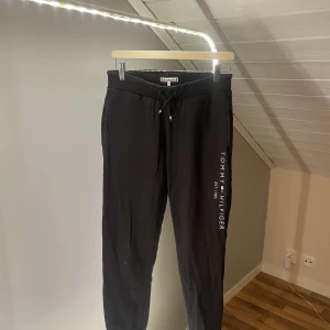 Svarta mjukisbyxor Tommy Hilfiger - Svarta mjukisbyxor från Tommy Hilfiger med logga längs benet och snörning i midjan. 