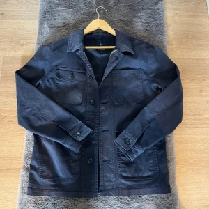 Mörkblå overshirt från Lindbergh - Snygg mörkblå overshirt från Lindbergh med klassisk krage, knäppning framtill och flera praktiska fickor. Använd fåtal gånger, inga defekter alls. Skriv vid intresse!