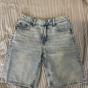 Ljusblå jeansshorts (jorts) - Säljer ett par ljusblå jeansshorts från H&M Divided i klassisk femficksmodell. De har en rak och loose passform, bälteshällor och knapp- samt dragkedjestängning. 