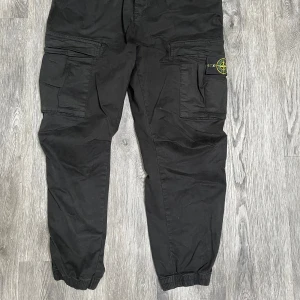 Stoneisland cargobyxor - Svarta cargobyxor från Stone Island med klassisk patch på benet. Byxorna har flera stora fickor, elastiska benslut och en loose passform. Tillverkade i bomull och perfekta för en streetwear-look. Använda men väl omhändertagna. Storlek medium/large.       Nypris 2499. 
