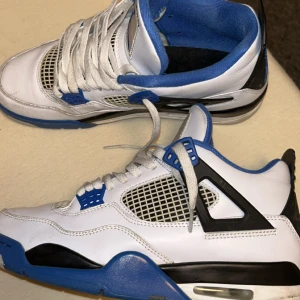 Nike Air Jordan 4 Retro Vit/Blå - Nike Air Jordan 4 Retro i vitt skinn med blå och svarta detaljer. Klassisk meshpanel på sidorna, blå innersula och Jumpman-logga på plösen. Snygg snörning och robust sula med synlig Air-enhet. Perfekta för dig som gillar streetwear och sneakers med ikonisk design. Storlek 43 är du skofan så kommer du att se om den är äkta eller falsk även crease skydd med för att skydda skorna så mycket som de bara går, tagit bra hand om skorna. Priset kan diskuteras 