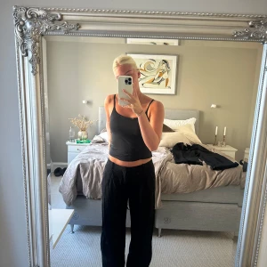 Svarta kostymbyxor från Lindex, strl 36 - Säljer ett par svarta kostymbyxor från Lindex i storlek 36. Byxorna har rak och loose passform med hög midja och bälteshällor. Materialet är mjukt och lätt, perfekt för en chill och stilren look. Passar dig som gillar klassiska och bekväma byxor.