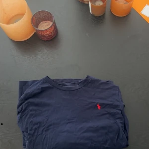 Mörkblå t-shirt från Polo Ralph Lauren - Snygg långärmad mörkblå t-shirt från Polo Ralph Lauren med klassisk röd logobrodyr på bröstet. Storlek L men passar mer m skulle jag säga, nypris 799 och mitt är 349 men pris kan självklart diskuteras!!!!