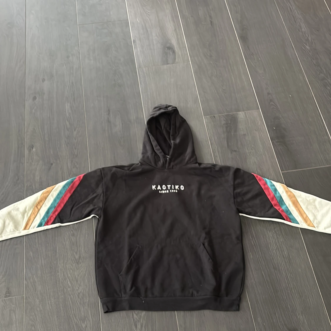 Svart hoodie från Kaotiko med färgglada ränder