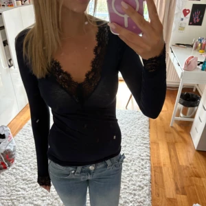 Mörkblå långärmad spetsblus - Säljer en mörkblå långärmad blus med djup v-ringning och snygga spetsdetaljer vid halsringning och ärmslut. Sitter tight och är perfekt för dig som gillar en feminin och stilren look. Jag säljer den då den inte längre kommer till användning 💕den är från Intimissimi och är i storlek m. Pris kan diskuteras 