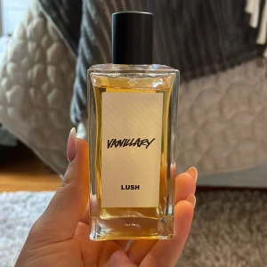 Lush Vanillary parfym 100ml - Lush Vanillary är en vegansk parfym med varm vanilj, tonkaböna och jasmin. Kommer i en stilren, rektangulär glasflaska med svart lock och vit etikett. Innehåller 100 ml handblandad parfym med eteriska oljor. Perfekt för dig som älskar söta och mjuka dofter.