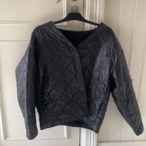 Svart quiltad jacka i syntet - Quiltad svart jacka med rutmönster och lång ärm. Jackan har en loose passform och är tillverkad i syntetmaterial. Den har ett hål på armen som går att fixa om man orkar, därför sänker jag pris. Köpt för 500