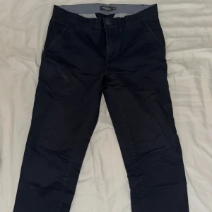 Mörkblåa chinos från dressmann Waist 30/ Length 30 - Snygga mörkblåa chinos från dressmann med en klassisk design. Byxorna har en normal passform och är tillverkade i ett bekvämt bomullsmaterial. Perfekta för en stilren look.