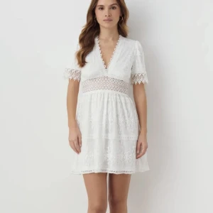 Vit spetsklänning med v-ringning - vit klänning med v-ringning och spetsdetaljer. Kortärmad design med broderier och spetsmönster. Perfekt inför studenten🤍