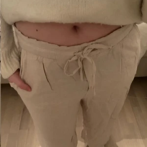 Beigea linnebyxor från h&m ☀️🙌🏼💗 - Säljer ett par bekväma beigea linnebyxor  med knytband i midjan. Byxorna har en loose passform och är perfekta för en avslappnad stil. De är tillverkade i ett mjukt material som ger en skön känsla. Står st 40 men passar mig som har S! Dom har en jätteliten fläck på vänster ben och det var knappt så jag såg det. Skriv för fler bilder💗🙌🏼☀️