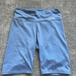Blå träningsshorts från Stronger - Säljer ett par blå träningsshorts från Stronger i storlek S. De är tillverkade av en mjuk och stretchig blandning av polyester och elastan, vilket gör dem perfekta för träning. Shortsen har en hög midja för extra komfort och stöd💕
