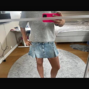 Blå jeanskjol - Trendig blå jeanskjol med råa kanter och en avslappnad look. Kjolen har en kort längd och en klassisk femficksdesign. Perfekt för en casual stil.