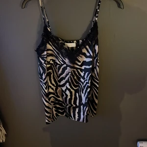 Zebramönstrad linnetopp från Samsa Collection - Snygg zebramönstrad linnetopp från Samsa Collection med spetsdetaljer vid halsringningen. Perfekt för en trendig look. Justerbara axelband för bästa passform.