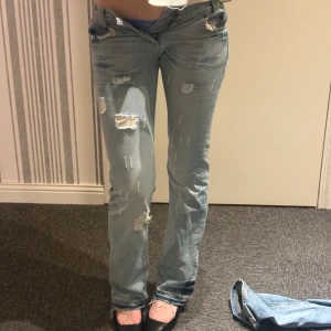Snygga bootcut jeans från replay! - Säljer ett par ljusa jeans med hål för en trendig look. De har en normal passform och är perfekta för en avslappnad stil. Jeansen har klassisk femficksdesign och knappgylf. Gylfen är öppen för att dem ej passar! Älskar hålen!! Pris kan diskuteras!! 