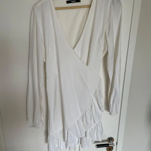 Vit omlottklänning från Bikbok  - Jättefin omlottklännings med knytning i midjan från Bikbok. Passar perfekt nu till studenten eller skolavslutning, använd endast fåtal gånger