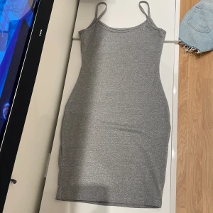 Grå ärmlös klänning, Storlek XS, aldrig använd. - Snygg grå ärmlös klänning med smala axelband. Klänningen har en tight passform och är gjord i ett mjukt material. 