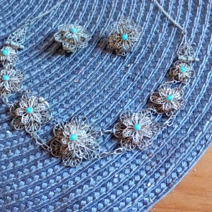 Blommigt halsband och örhängen clips i silver Filligran arbete med Turkoser. - Elegant smyckesset med ett halsband och matchande örhängen clips i silver. Båda delarna har ett intrikat blommönster med turkosa detaljer i mitten av varje blomma. Perfekt för att ge en touch av vintage charm till din stil.