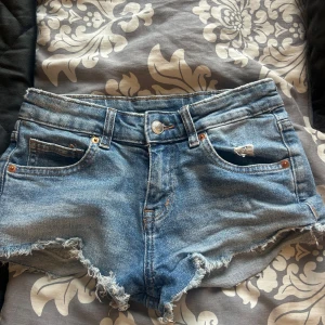 Blå lågmidjade  jeansshorts  - Säljer ett par snygga blå lågmidjade jeansshorts med fransiga kanter. Perfekta inför sommaren!🩷