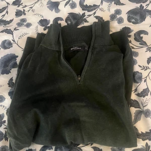 Mörkgrön tröja med dragkedja från Daniel Hechter - Säljer en stilren mörkgrön tröja från Daniel Hechter. Tröjan har en praktisk dragkedja vid halsen och långa ärmar. Perfekt för kyligare dagar.