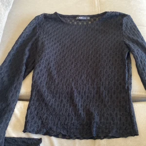 långärmad spets tröja - Säljer en elegant svart långärmad spets tröja med ett unikt mönster. Toppen har en rund halsringning och är perfekt för både vardag och fest. Materialet är lätt och luftigt, vilket gör den bekväm att bära. Passa på att köpa denna stilrena topp! 🖤