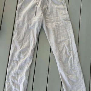 Beige linnebyxor från Jack and Jones  - Säljer ett par bekväma grå mjukisbyxor med elastisk midja och snörning. Perfekta för en avslappnad dag hemma eller en snabb tur till affären. Byxorna har en rak passform och är tillverkade i mjukt material. Priset är inte gjutet i sten så hör gärna av dig!