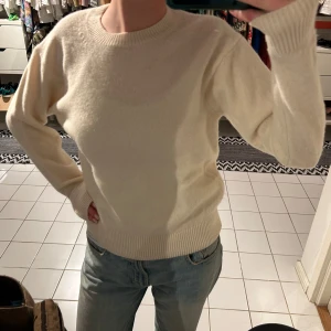 Vit stickad tröja  - Säljer en stilren vit stickad tröja med rund hals och långa ärmar. Perfekt för kyligare dagar och lätt att matcha med olika outfits. Tröjan har ribbade muddar vid ärmslut och nederkant för en bekväm passform. Från uniqlo