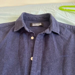 Mörkblå skjorta från Gabba - Snygg mörkblå skjorta från Gabba med klassisk krage och knappar framtill. Skjortan har långa ärmar och är tillverkad i ett mjukt material som ger en bekväm känsla. Perfekt för en stilren look.(pris kan alltid diskuteras)