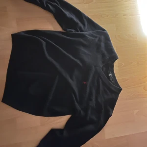 Svart kashmirtröja från Ralph Lauren - Säljer en elegant svart kashmirtröja från Ralph Lauren. Tröjan har en v-ringad design och ett diskret rött broderat märke på bröstet. Perfekt för en stilren look. Den passar S bäst 