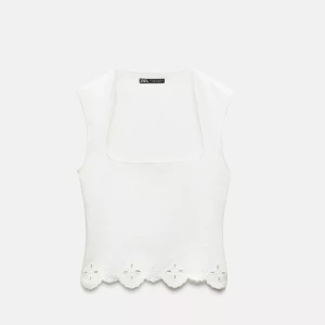 Stickad topp med fyrkantig krage i stretch  - Säljer en stilren vit ärmlös topp från Zara med en unik fyrkantig halsringning. Toppen har en vacker blommig kantdetalj längst ner som ger en söt touch. Perfekt för varma dagar! Aldrig använd då den är lite för liten för mig! 