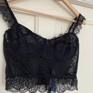 Svart spetslinne - Snyggt svart spets linne perfekt som festtopp! Aldrig använd, med prislappen kvar.