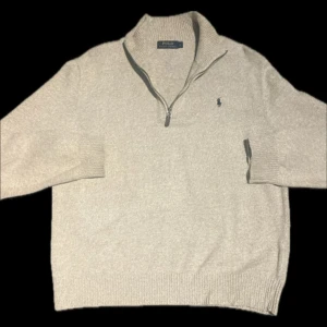 Beige tröja med dragkedja från Polo Ralph Lauren - Säljer en stilren beige tröja från Polo Ralph Lauren med dragkedja vid halsen. Tröjan har långa ärmar och en liten broderad logotyp på bröstet. Perfekt för en avslappnad och snygg look. I storlek L. Inga defekter eller fläckar. 