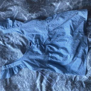 Blå- och vitrandig topp från Pieces - Säljer en söt blå- och vitrandig topp från Pieces. Klänningen har volangdetaljer vid axlarna och en smockad midja för en bekväm passform💙använd ett fåtal gånger 