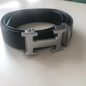 Svart bälte med silverfärgat H-spänne - Snyggt svart bälte med ett stilrent silverfärgat H-format spänne. Perfekt för att ge en elegant touch till din outfit.