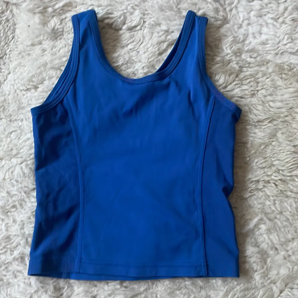 Säljer en snygg blå linnetopp från Röhnisch. Perfekt för träning eller en varm sommardag. Toppen har en enkel design med breda axelband och är tillverkad i ett mjukt och stretchigt material.. Yläosat.