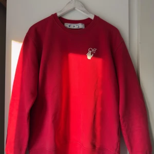 Röd sweatshirt från Off-White - Säljer en snygg röd sweatshirt från Off-White med deras ikoniska pilar tryckta i vitt på baksidan. Tröjan har en rund halsringning och långa ärmar. Perfekt för en stilren och modern look.
