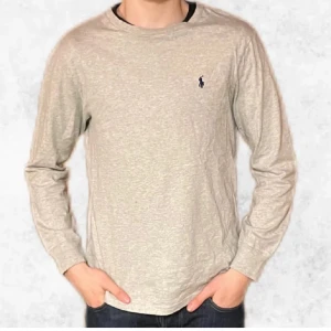Grå långärmad tröja från Polo Ralph Lauren - Säljer en stilren grå långärmad tröja från Polo Ralph Lauren. Tröjan har en klassisk design med en liten broderad logotyp på bröstet. Perfekt för en avslappnad och snygg look.
