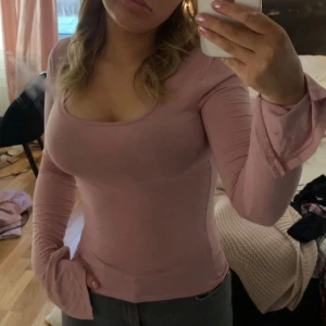 Rosa långärmad topp - Säljer en rosa långärmad topp med en rundad halsringning. Toppen har en tight passform och är perfekt för en stilren look. Ärmarna har en liten volangdetalj vid ärmsluten. Liten fläck som man ser på sista bilden!