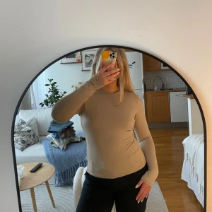 Beige långärmad topp från H&M - Säljer en stilren beige långärmad topp från H&M. Perfekt för lager-på-lager eller som den är. Toppen har en rund halsringning och är gjord i ett mjukt material som känns skönt mot huden. Passar till många olika outfits!