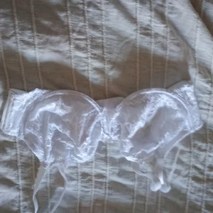 Vit spets-bh med bygel - Säljer en elegant vit bh med spetsdetaljer. Den har justerbara axelband och en klassisk design som ger ett romantiskt intryck. Perfekt för att känna sig extra fin. Med bygel.