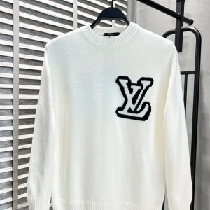 Vit stickad tröja från Louis Vuitton - Säljer en stilren vit stickad tröja från Louis Vuitton med ett stort svart LV-märke på bröstet. Tröjan har en rund halsringning och långa ärmar, perfekt för kyligare dagar. Ett måste för modeälskare! 🖤