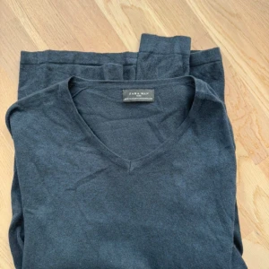 Svart v-ringad tröja från Zara Man - Säljer en stilren svart v-ringad tröja från Zara Man. Tröjan är tillverkad i en mjuk blandning av viskos och polyamid, vilket ger en skön känsla mot huden. Perfekt för en avslappnad men ändå snygg look. Storlek M!