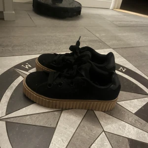 Svarta sneakers med platåsula - Snygga svarta sneakers med en tjock, brun platåsula. Använda fåtal gånger 