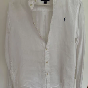 Vit linneskjorta från Polo Ralph Lauren - Klassisk vit skjorta i linne från Polo Ralph Lauren med lång ärm och knappar framtill. Skjortan har den ikoniska broderade loggan på bröstet och en avslappnad passform. Perfekt för en clean och stilren look och inför sommaren. Säljer för 259 men pris går att diskutera. Storleken är mindre än XL i modellen
