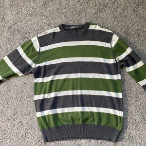 Randig tröja från Race Marine, grön/grå - Snygg randig tröja från Race Marine i storlek S. Tröjan har breda horisontella ränder i grönt, grått och vitt, rund halsringning och ribbade muddar. Perfekt för dig som gillar en avslappnad men stilren look.