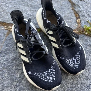 Adidas Ultraboost svarta sneakers - Svarta Adidas Ultraboost sneakers med vita detaljer och stickat mönster i vitt. Väl använda och mycket omtyckta. Kan säkert komma till använding hos någon annan!