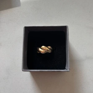 Guldig chunky ring med tvinnad design - Säljer en snygg ring i guldton med tvinnad, lite knutliknande design. Ej justerbar. Vet inte om man blir grön av den eller om den rostar. Aldrig använd. OBS! Asken medföljer ej! Läs gärna bio💕