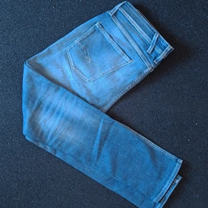 Replay Anbass Slim Fit Jeans Blå W32 - Säljer ett par Replay Anbass slim fit jeans i klassisk blå tvätt. Jeansen har fem fickor, snygga kontrastsömmar och Replay-logga på bakfickan. Modellen är smal och sitter snyggt längs benen. Sista bilden visar smått slitage vid höger knä