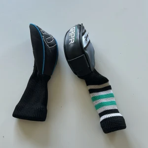 Golf headcovers TaylorMade & Wilson - Två snygga golfheadcovers – ett från TaylorMade i svart och silver med broderad logga, och ett från Wilson i svart med blå kant och vit brodyr. Båda har stickad, svart socka, det ena med ränder i vitt, svart och grönt. Perfekt för att skydda dina klubbor med stil. 50 kr st eller 90 för båda.Kan hämtas upp i Huddinge annars Exklusive frakt